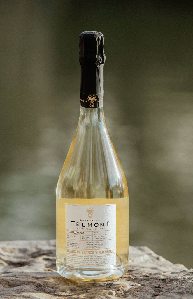 A lifestyle photo of a bottle Blanc de Blancs Vinotheque on a rock surface
